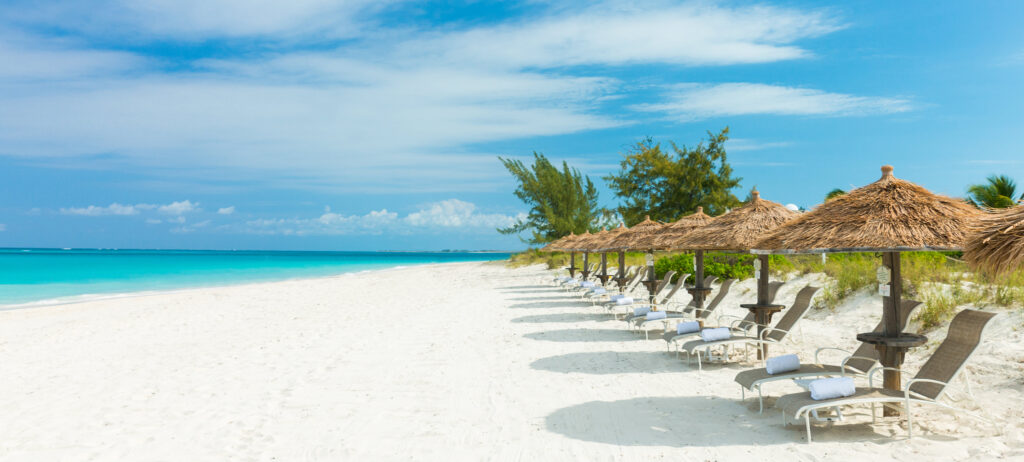 A row of beach palapas on the right and the ocean on the left.