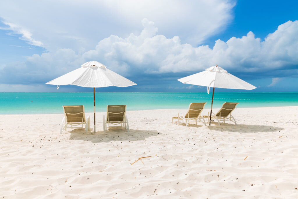 Two Umbrellas with chairs on Sands Beach with ocean in background