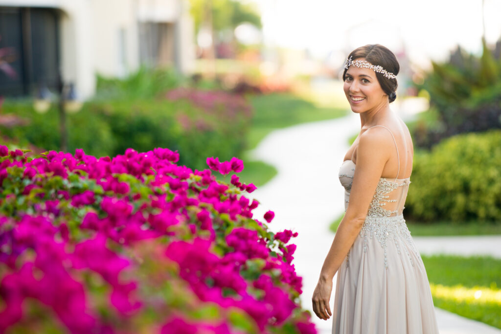 Bride turning back to pose next to pink flower bush