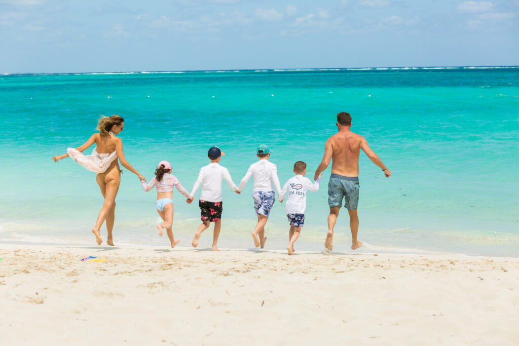 Family with four kids holding hands walking into the ocean